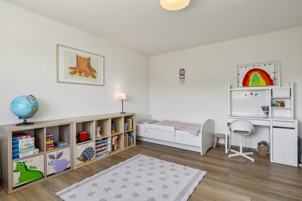 Bewohnte Immobilie, gestyltes Kinderzimmer mit Bett und Regal mit Spielsachen und weisser Pult.